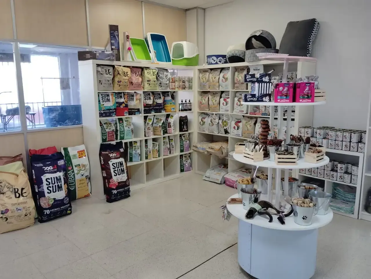 Interior de una tienda de mascotas con estantes llenos de alimentos y suministros para mascotas.