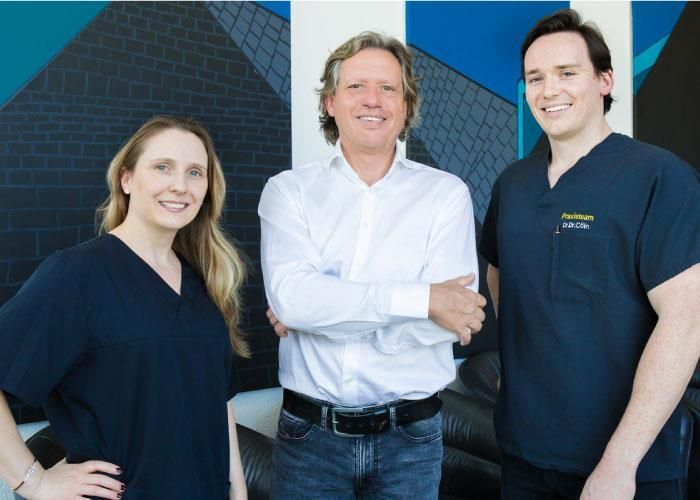 Zwei Männer und eine Frau posieren mit verschränkten Armen für ein Foto