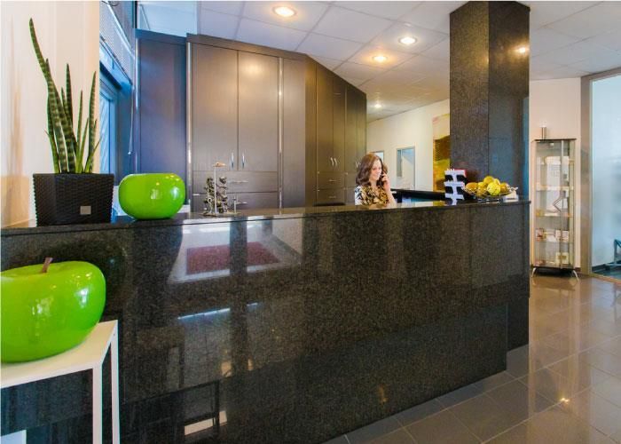 Eine Frau sitzt an einem Tresen in einem Empfangsbereich.