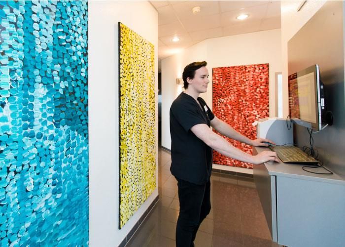 Ein Mann im OP-Kittel benutzt einen Laptop in einem Flur