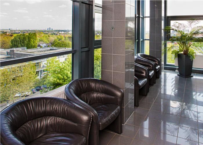 Eine Reihe Ledersessel stehen in einem Wartezimmer neben einem Fenster.