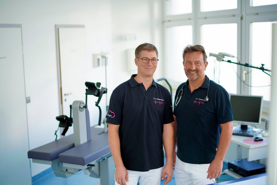 Zwei Männer stehen nebeneinander in einem Krankenhauszimmer.