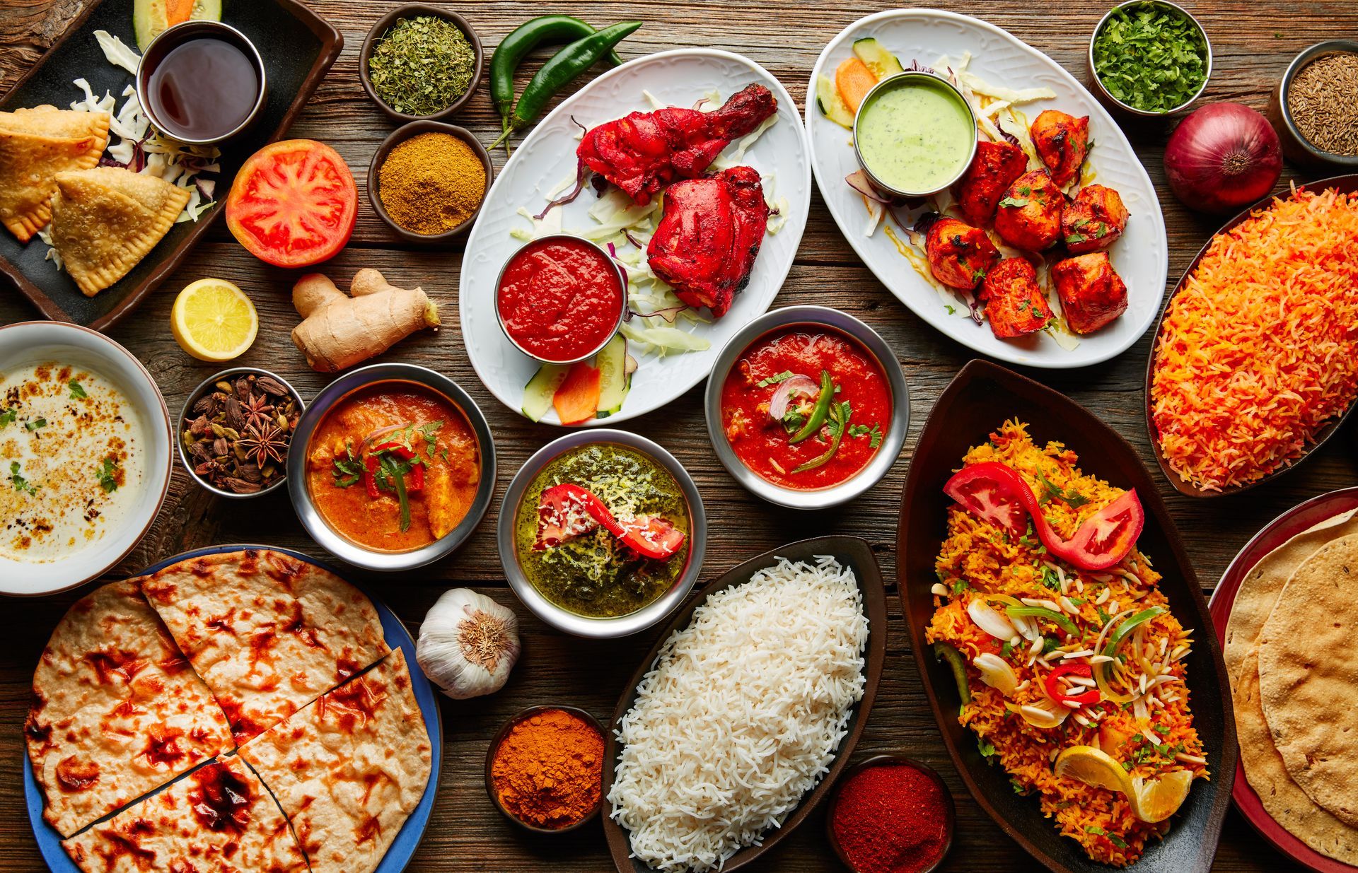 Plusieurs mets indiens arrangés sur une table : riz, viandes, curry, etc.