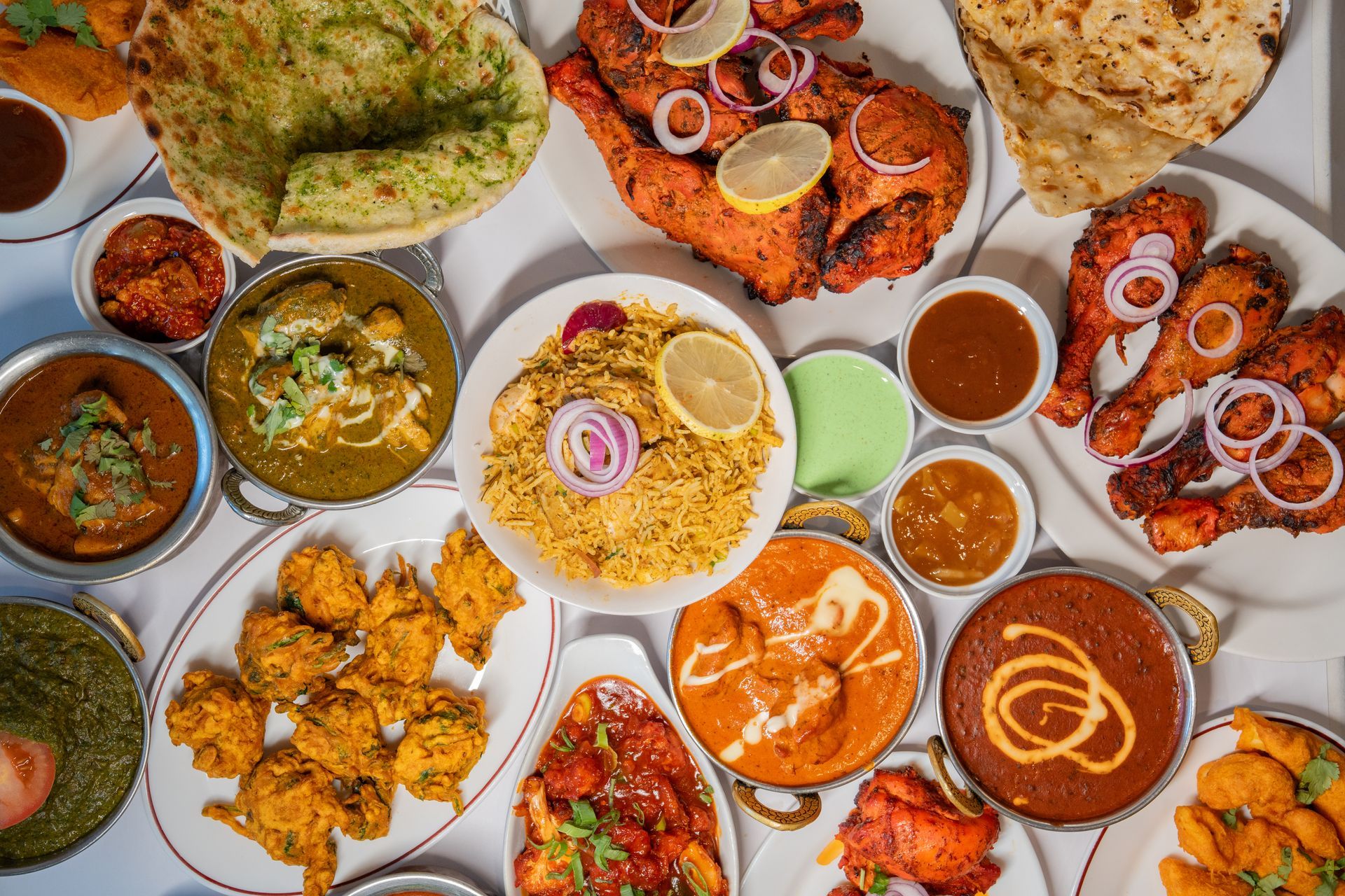 Un assortiment de plats et d'accompagnements indiens : viandes grillées, naans, plats au curry et riz.