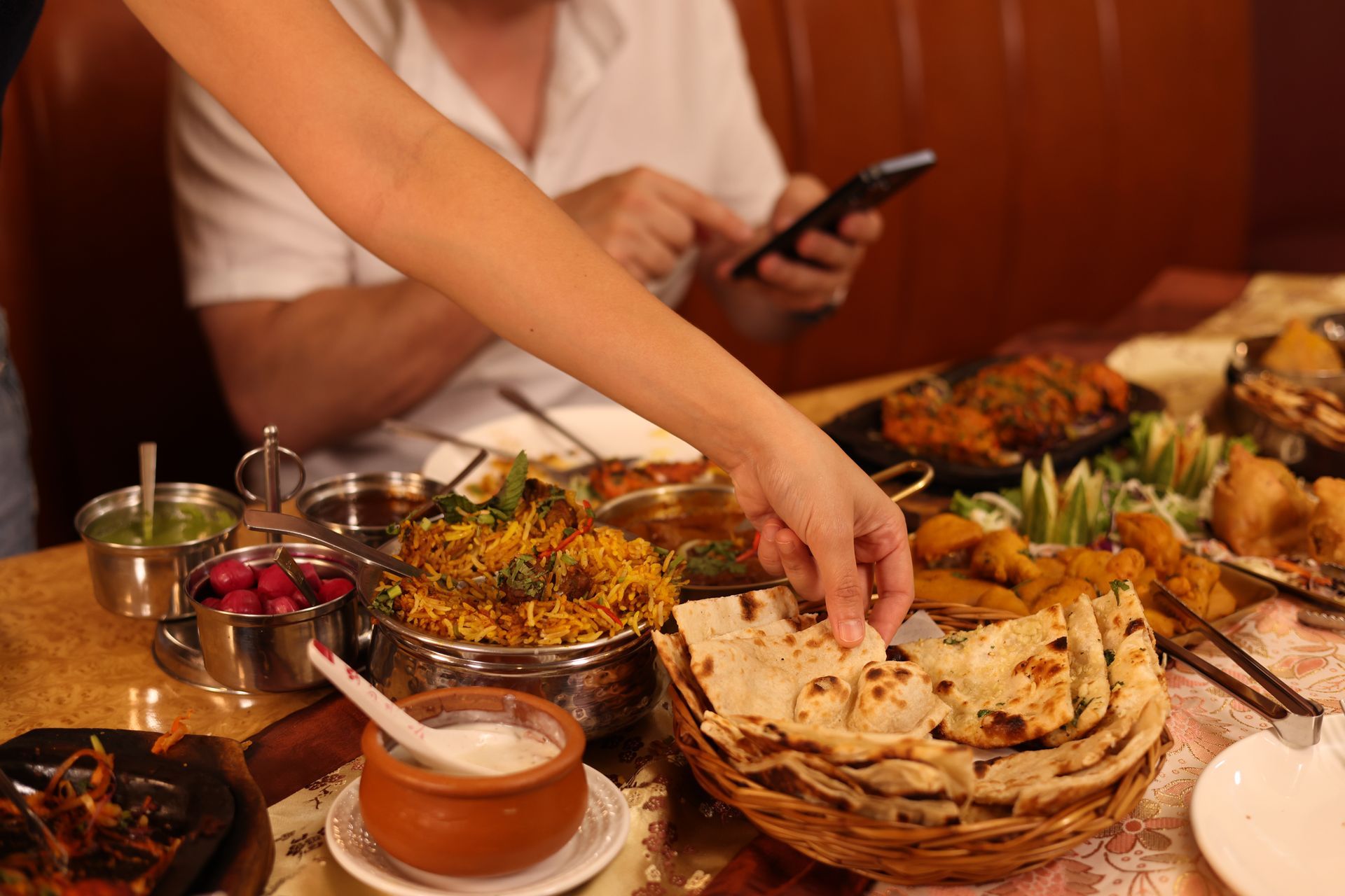 Une personne dans un restaurant se sert un morceau de naan.
