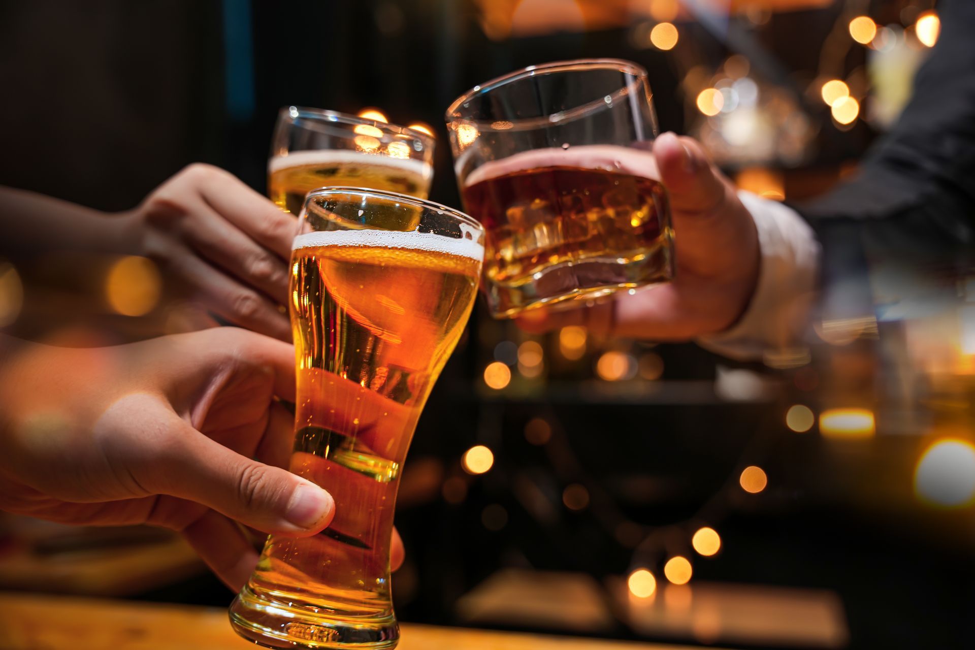 Trois personnes trinquent avec leurs verres de boissons alcoolisées.