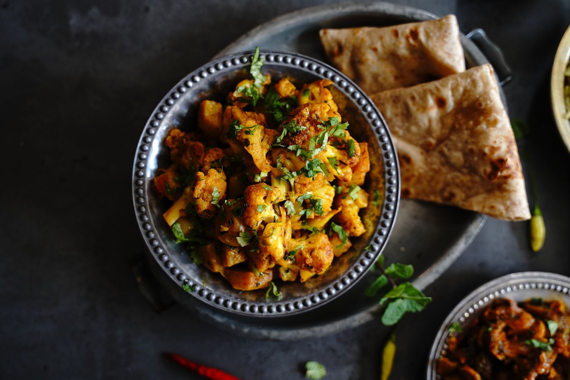 Aloo gobi servi dans un bol, accompagné de naan.