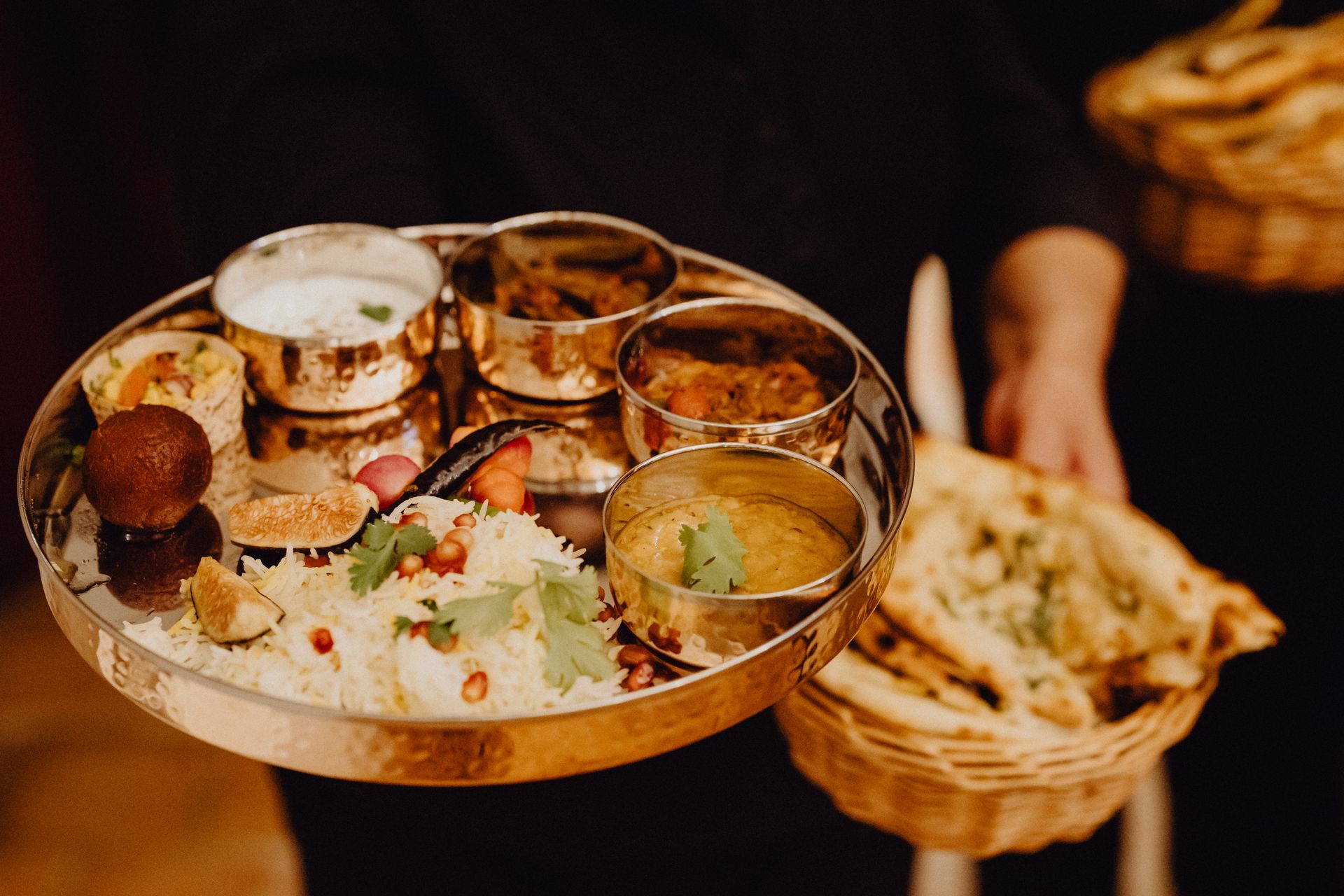 Un plateau en laiton garni de plats indiens et de naans.