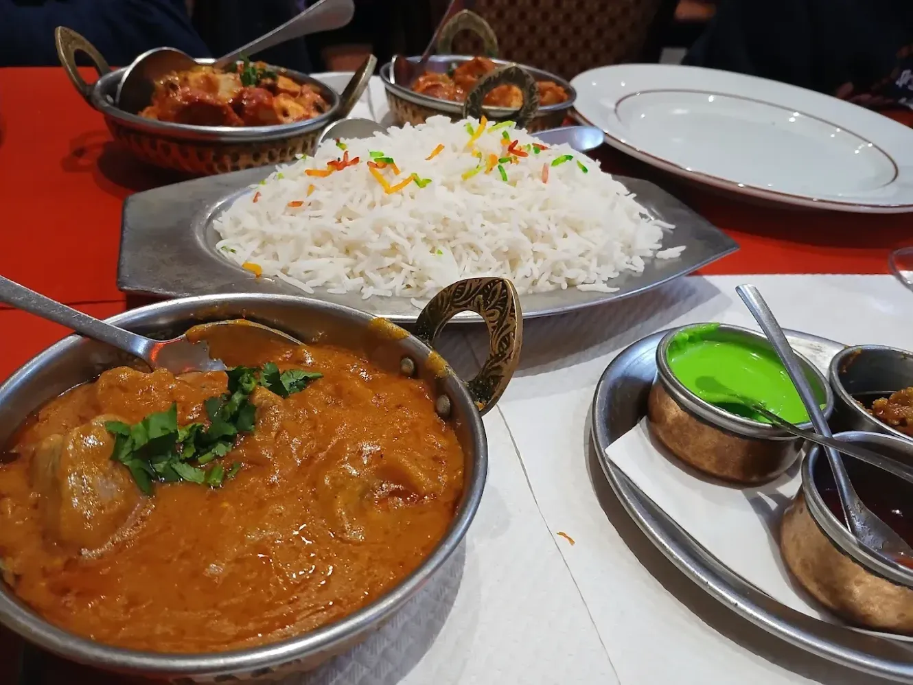 Un repas indien composé de curry, de riz, de naans et de chutneys, servi dans des bols en métal.