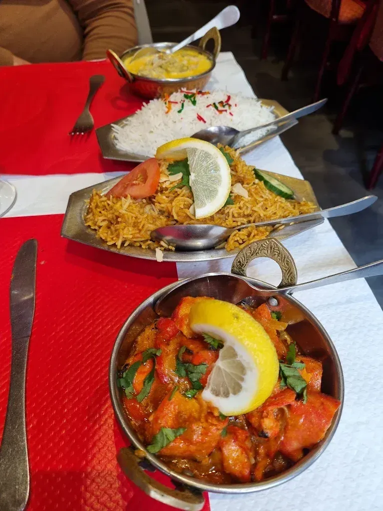 Un repas indien composé de biryani, de currys et de riz servis dans des bols en métal.