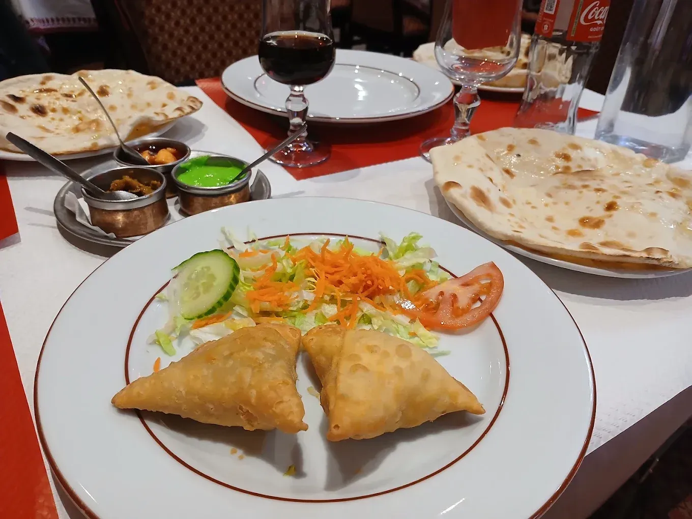 Des samosas indiens servis avec une salade verte et des naans.