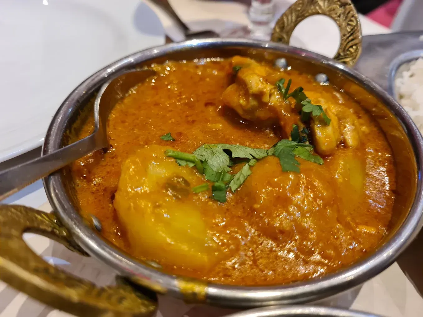 Un petit bol de curry aux pommes de terre, servi avec une cuillère.
