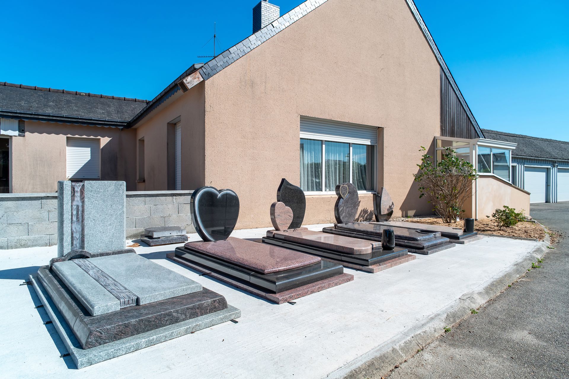 Pierres tombales exposées à l'extérieur d'un bâtiment marron clair par une journée ensoleillée.
