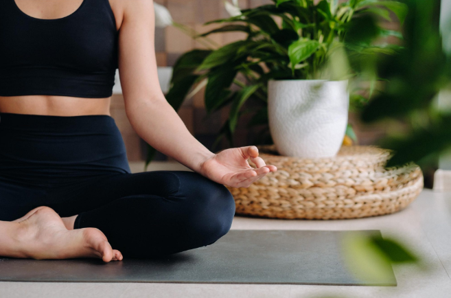 Una mujer está sentada en una esterilla de yoga en posición de loto.