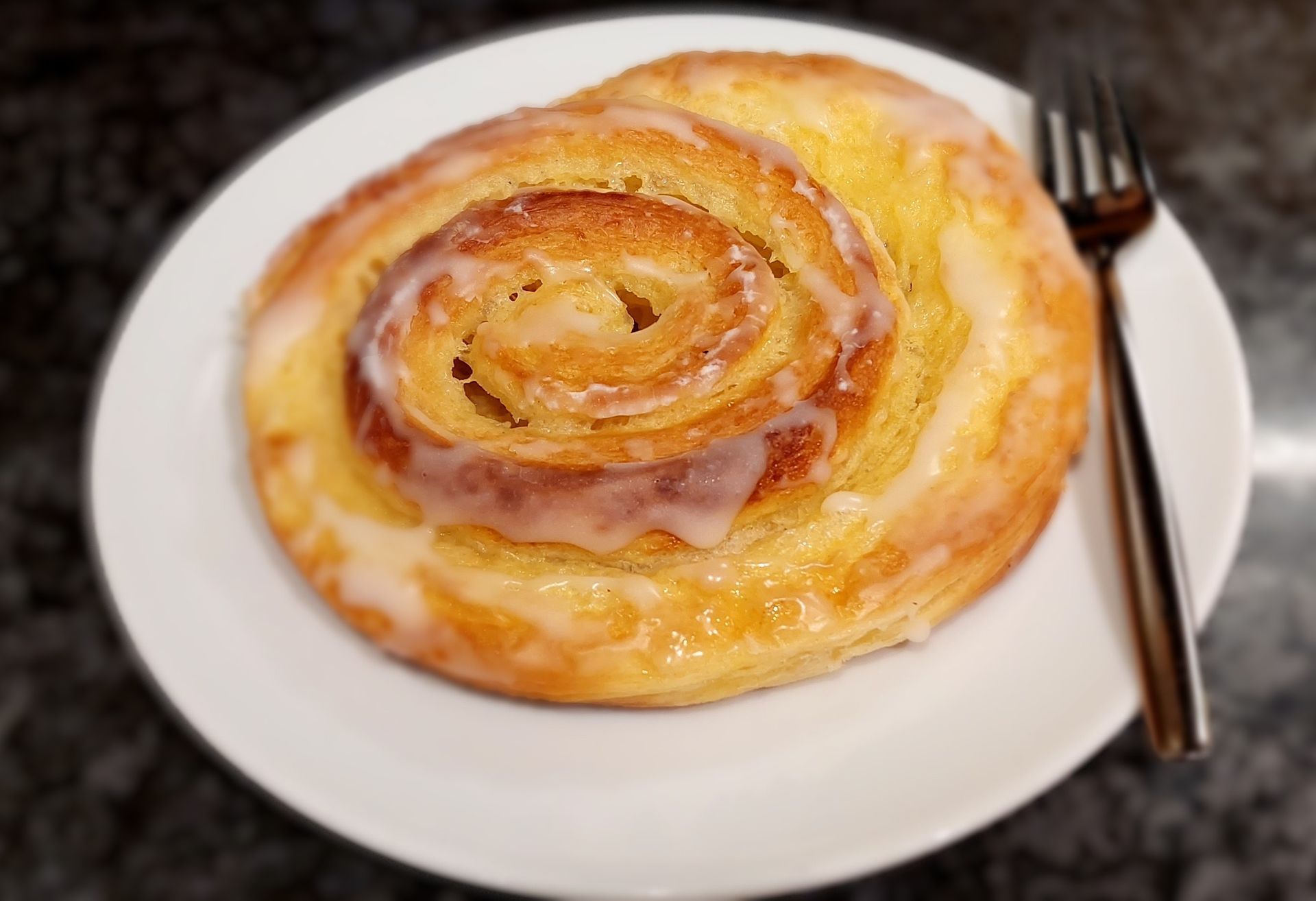 Ein Strudel liegt mit einer schwarzen Gabel auf einem Teller