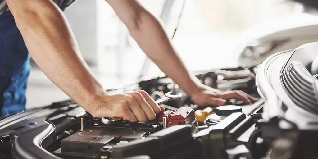 Un hombre está trabajando en el motor de un coche en un garaje.