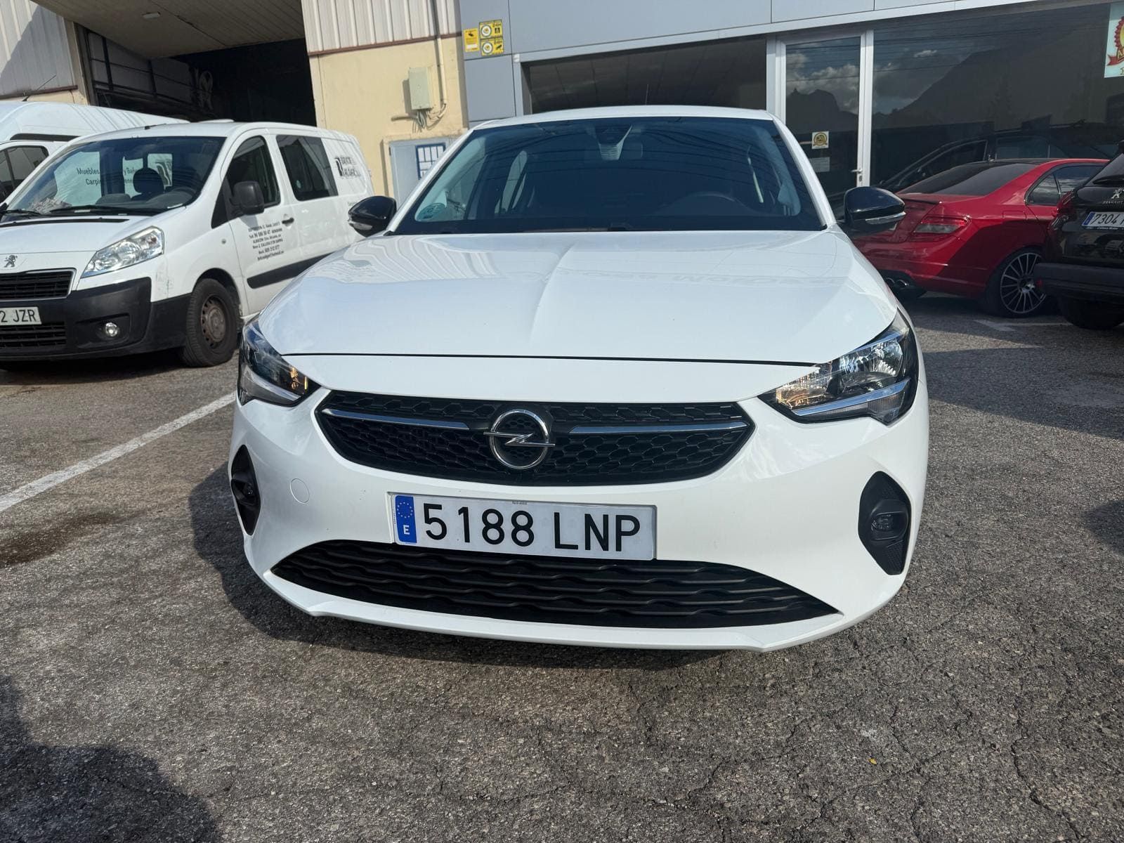 Coche Opel Corsa blanco aparcado en un aparcamiento; la matrícula indica 5188 LNP.