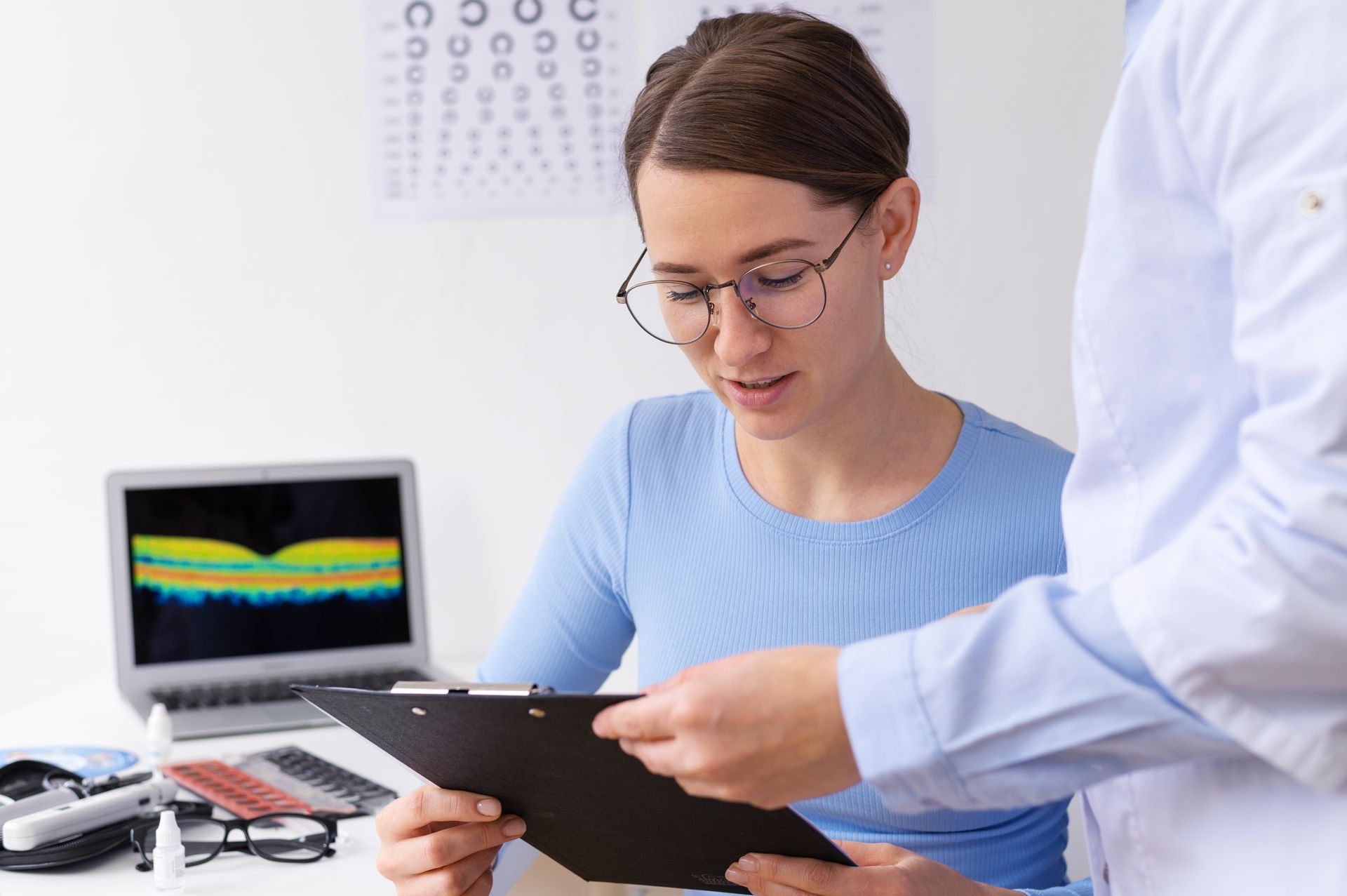 Mujer en un examen de la vista, mirando la historia clínica con el médico.