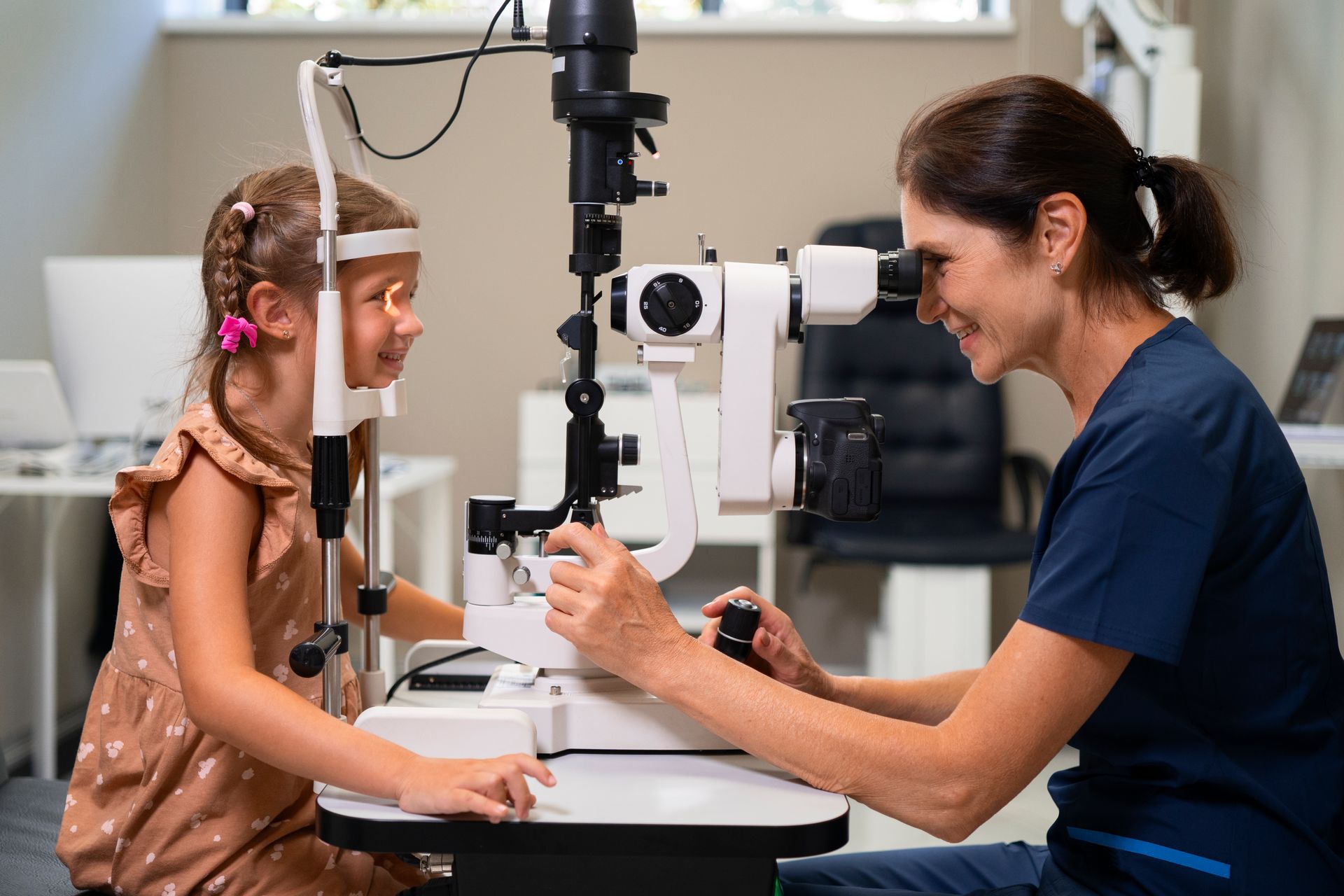 Optometrista examina los ojos de una niña con un dispositivo de lámpara de hendidura en un entorno clínico.