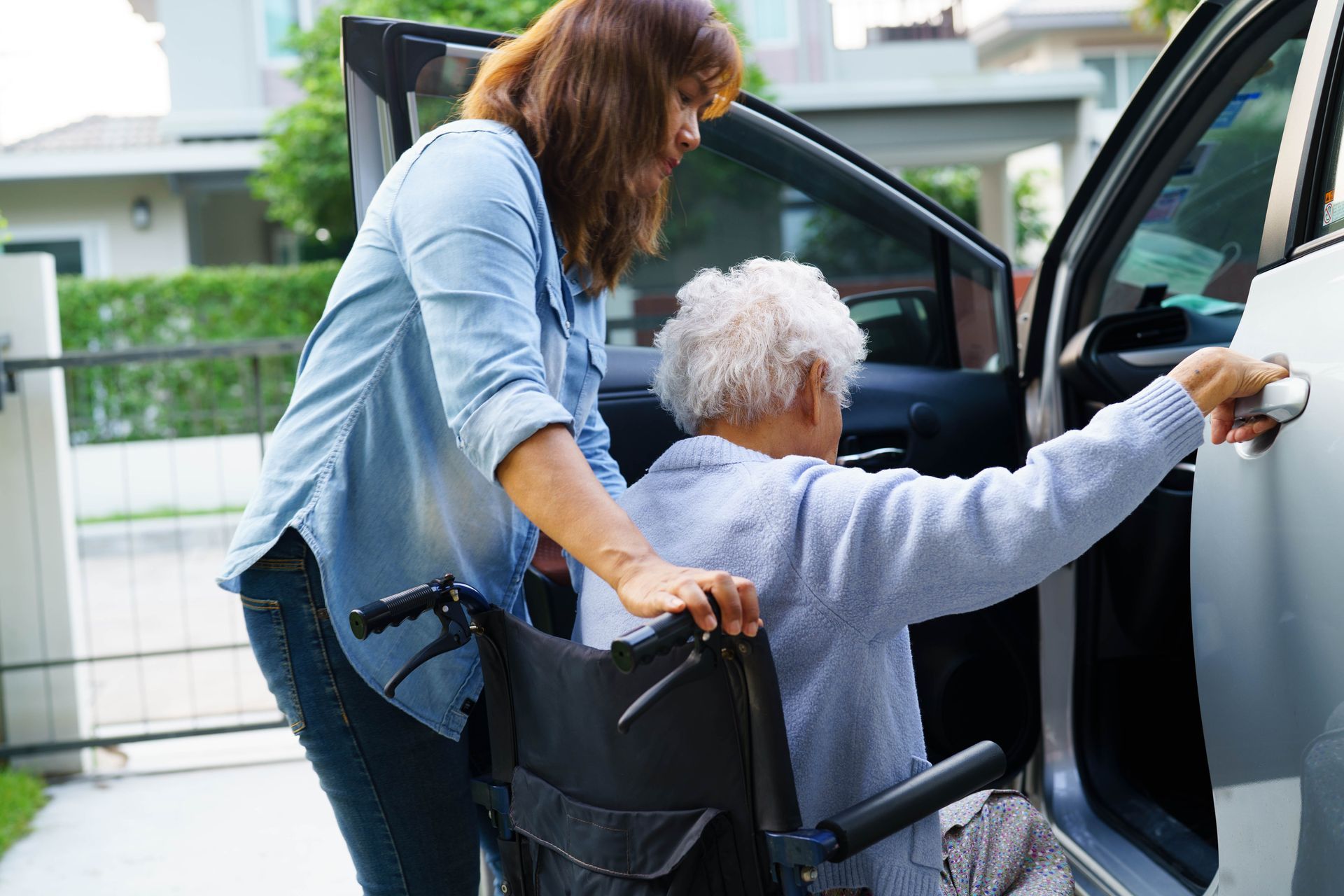 Femme qui aide une personne âgée à monter dans une voiture.