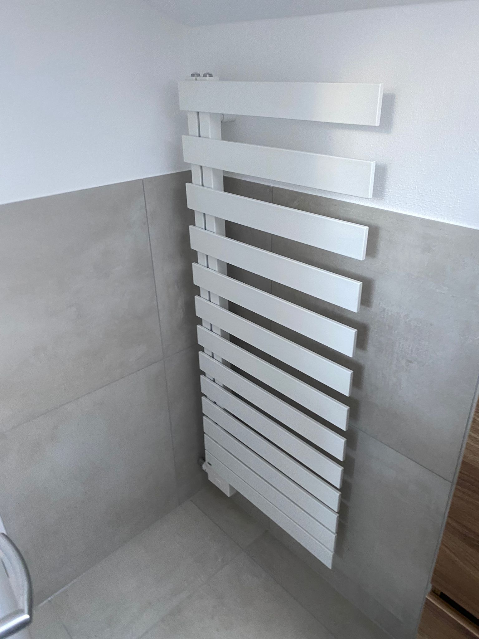 Eine Person mit weißem Hut und blauem Overall fliest eine Wand in einem Badezimmer. Werkzeuge liegen auf einem Tisch bereit.