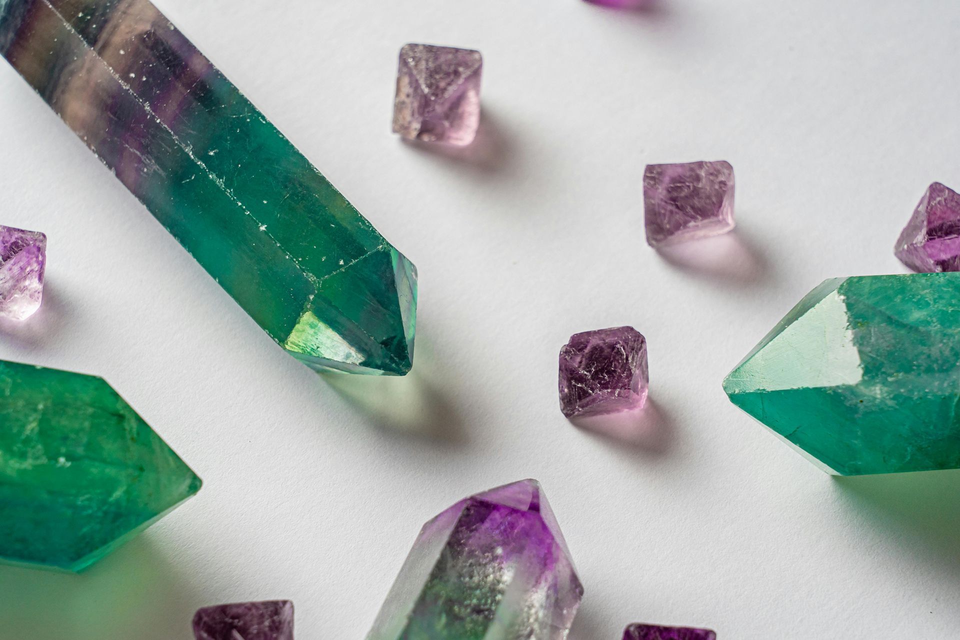 A group of purple and green crystals on a white surface.
