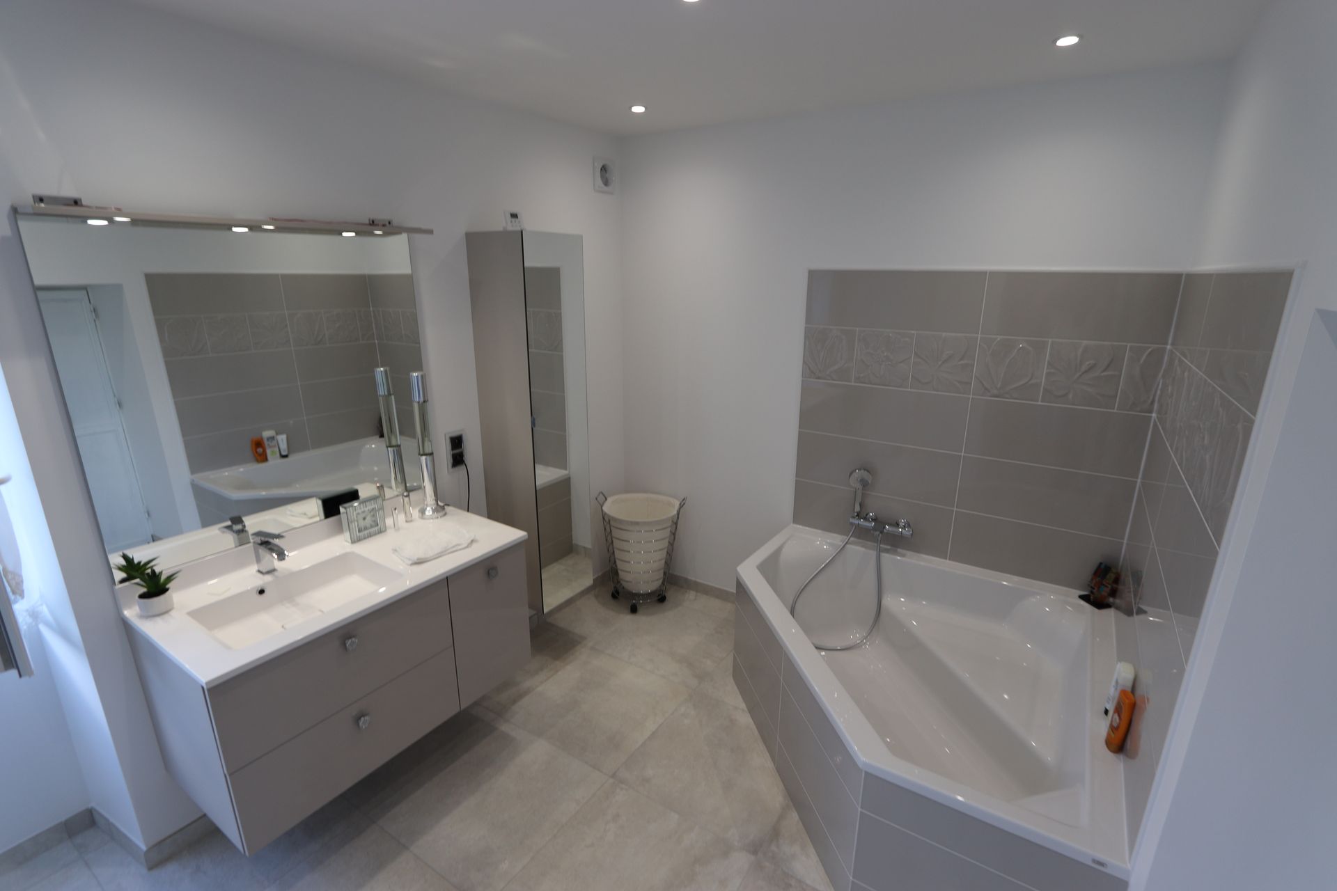 Une baignoire d'angle avec un meuble sous vasque dans une salle de bains