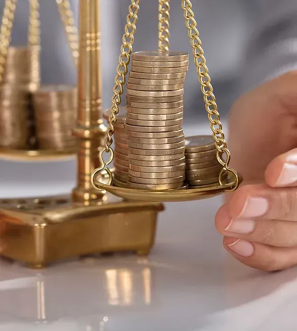 Una persona sostiene una balanza con pilas de monedas sobre ella.
