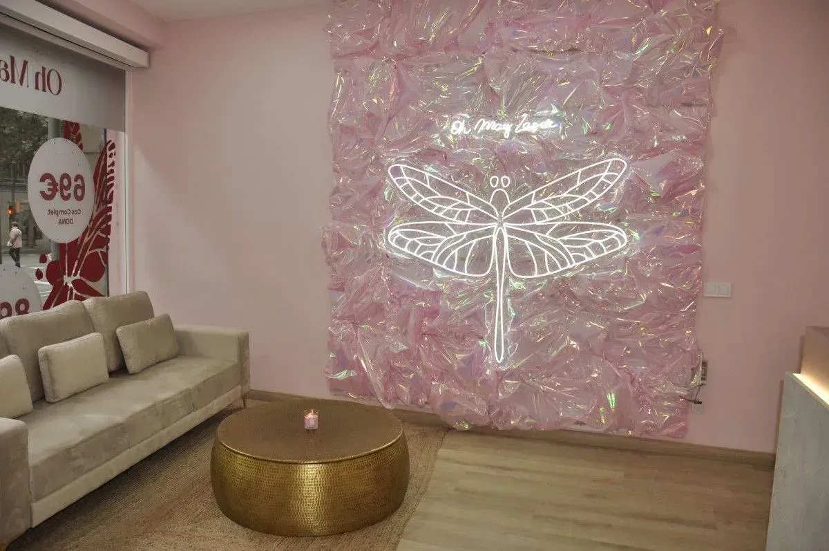 Sala rosa con un sofá beige, una mesa de centro dorada y un gran cuadro brillante en la pared.