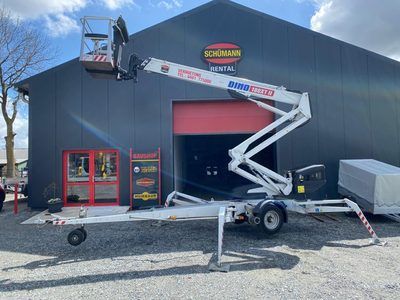 Vor einem Gebäude steht ein Kran auf einem Anhänger.