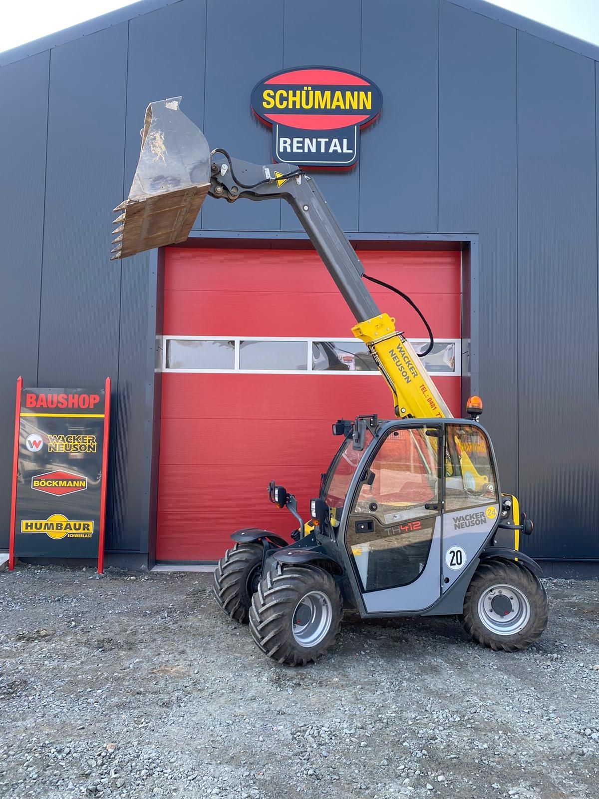 Ein gelb-grauer Gabelstapler mit einer Schaufel auf weißem Hintergrund.