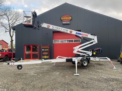 Vor einem Gebäude steht ein Kran auf einem Anhänger.