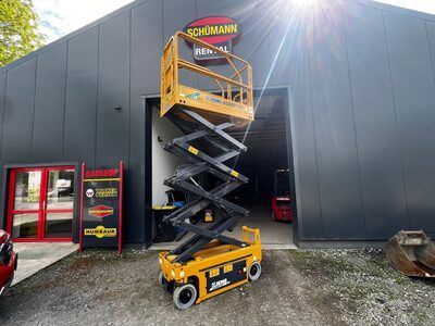 Vor einem Gebäude steht eine Scherenhebebühne.