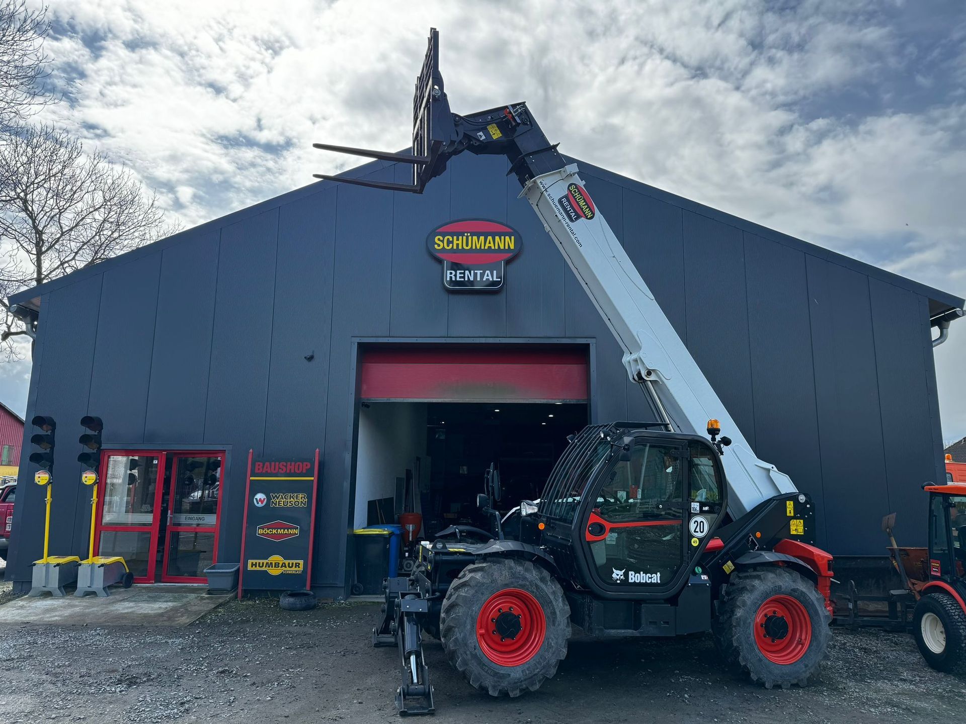 Vor einem Gebäude steht ein Teleskoplader.