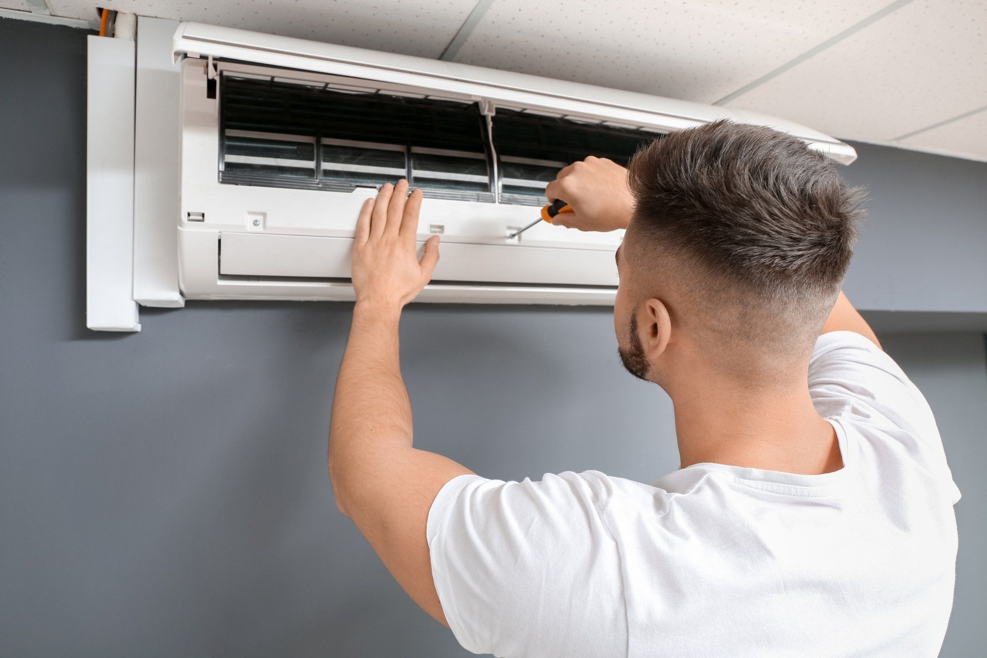 Un homme en train de réparer une climatisation