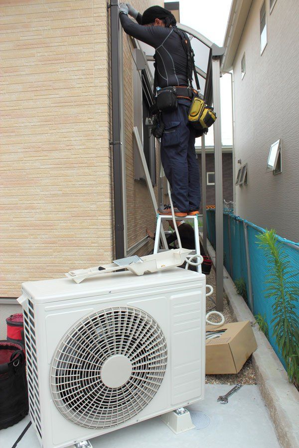 Un homme en train de réparer une climatisation extérieure