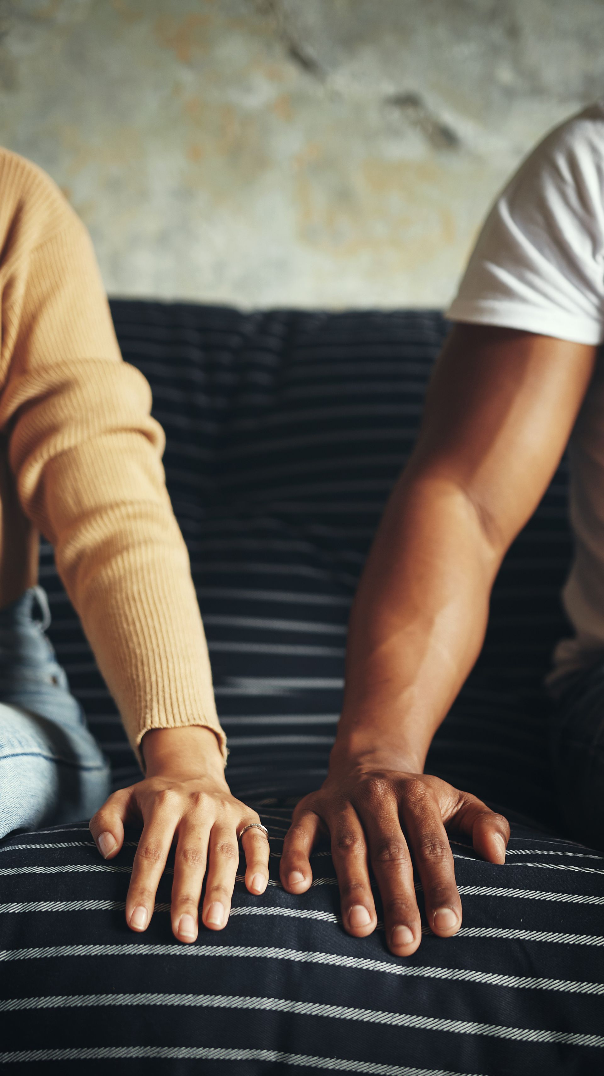 Deux avant-bras en gros plan d'un couple sur un canapé.