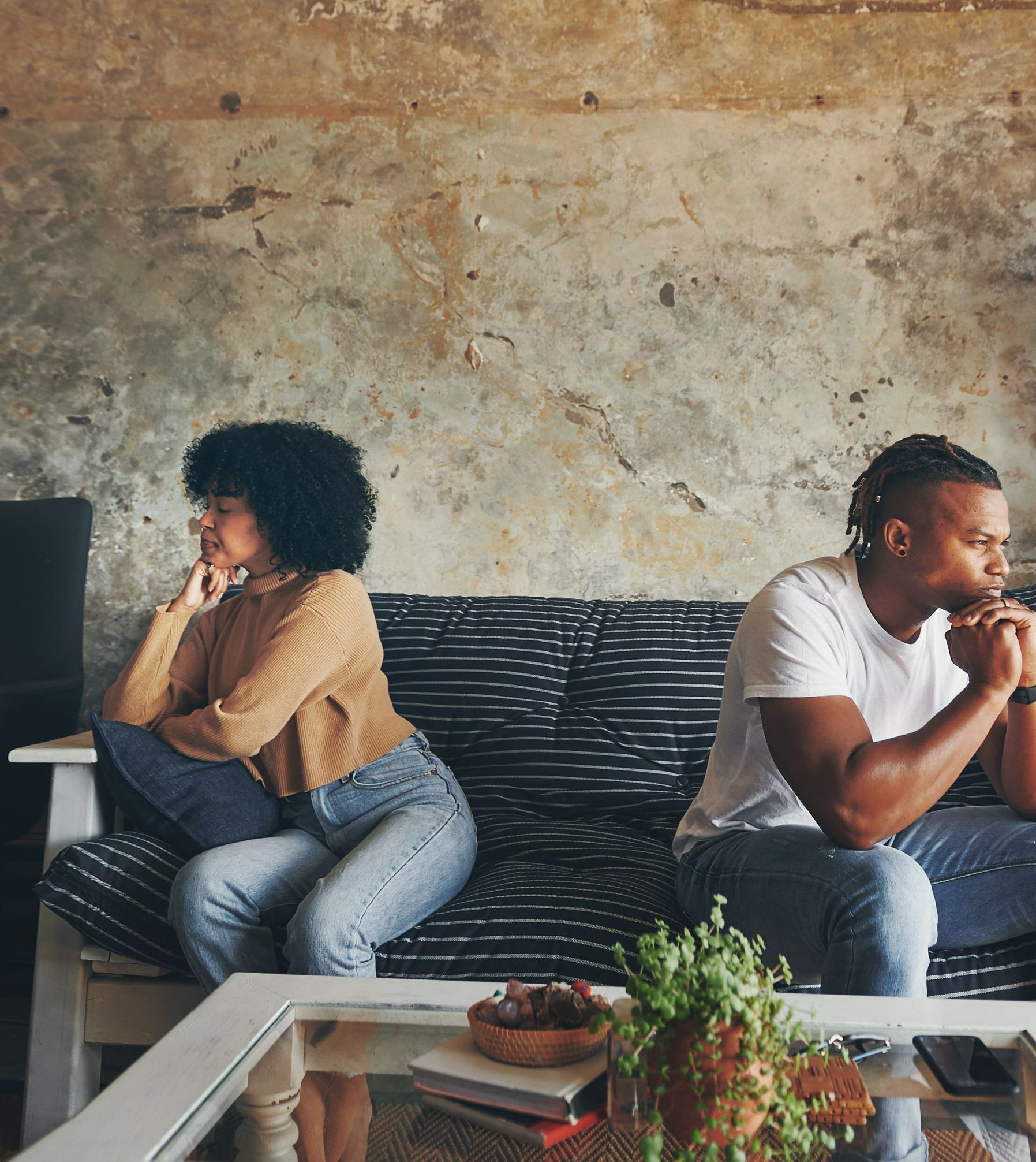 Un couple en conflit assis sur un canapé.