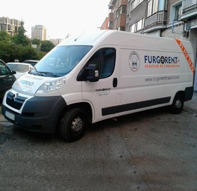 Una furgoneta blanca Furgonet está estacionada frente a un edificio.