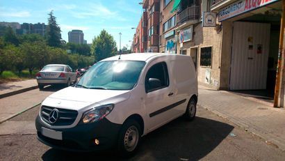 Una camioneta blanca está estacionada al costado de la carretera frente a un edificio.