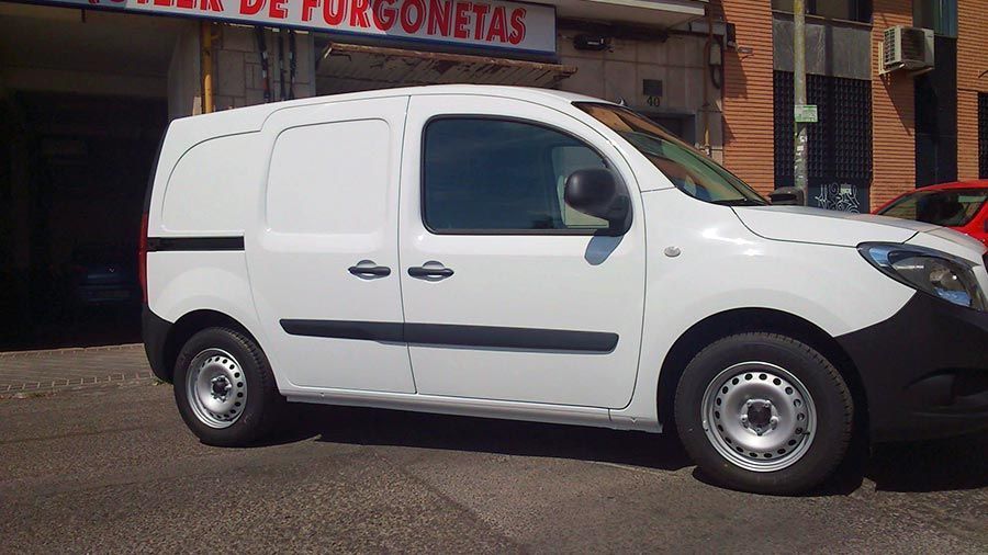Una furgoneta blanca está estacionada frente a una tienda llamada furgonetas
