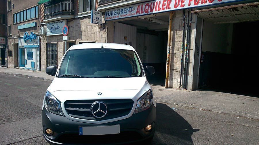 Una camioneta Mercedes blanca está estacionada frente a un edificio.