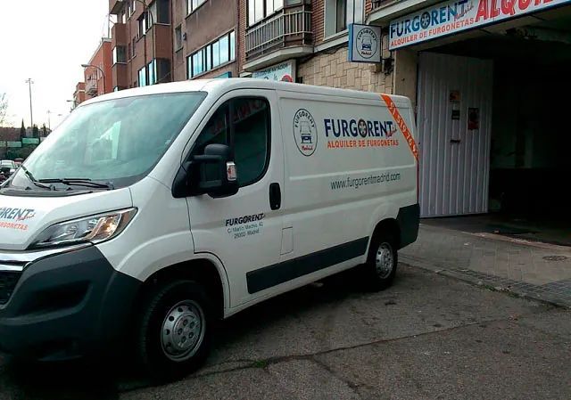 Una camioneta blanca está estacionada frente a un edificio.