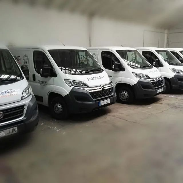 Una fila de furgonetas blancas están estacionadas en un almacén.