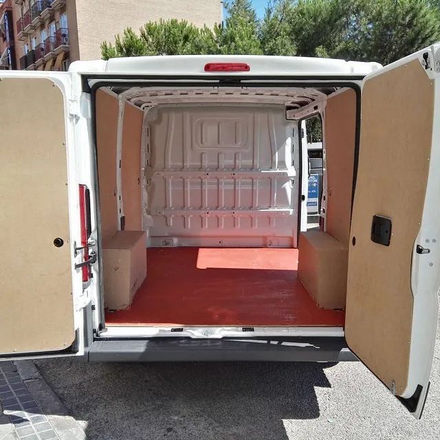 La parte trasera de una furgoneta blanca con las puertas abiertas.