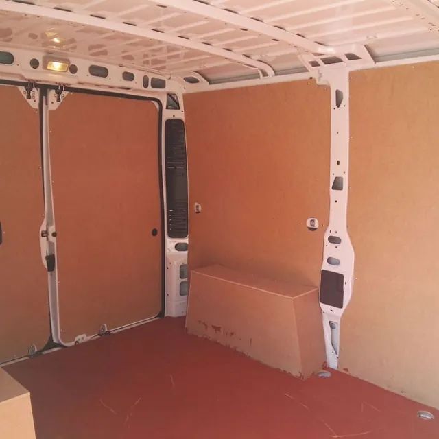 El interior de una furgoneta vacía con suelo rojo.