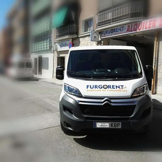 Una furgoneta blanca Furgonet está estacionada frente a un edificio.