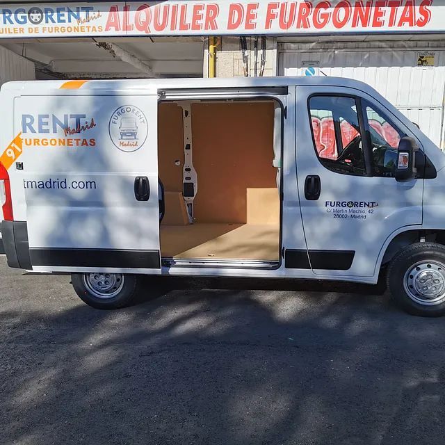 Una furgoneta blanca está estacionada frente a un cartel que dice rgorent alquiler de furgonetas