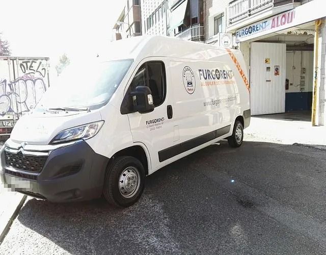 Una camioneta blanca está estacionada frente a un edificio.