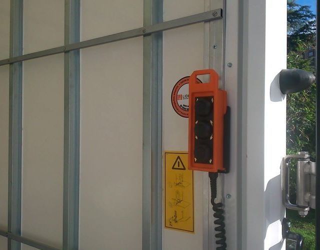 Un control remoto naranja está pegado a una pared blanca.